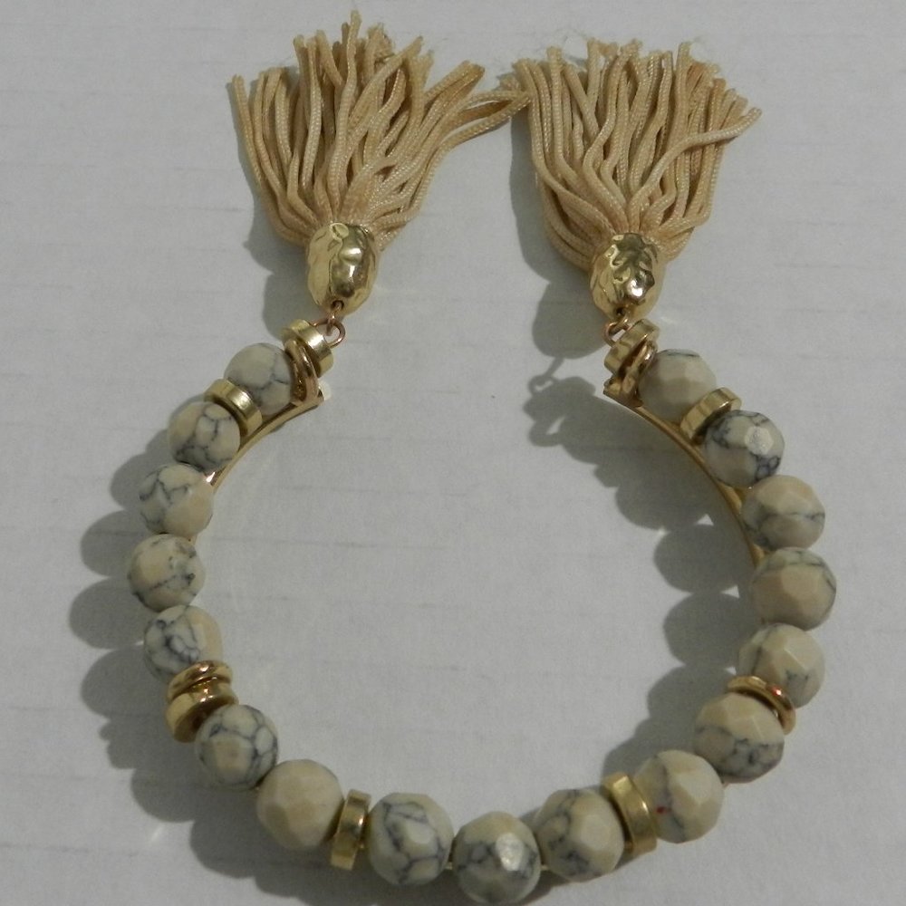 Neutral tones faceted bead bracelet with tasseled ends. Goldtone, tan, gray